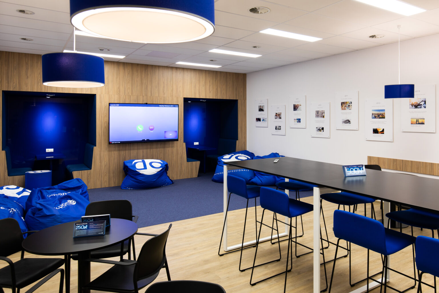 Strefa co-workingowa Expondo Zielona Góra z monitorem do wideokonferencji i niebieskimi siedziskami