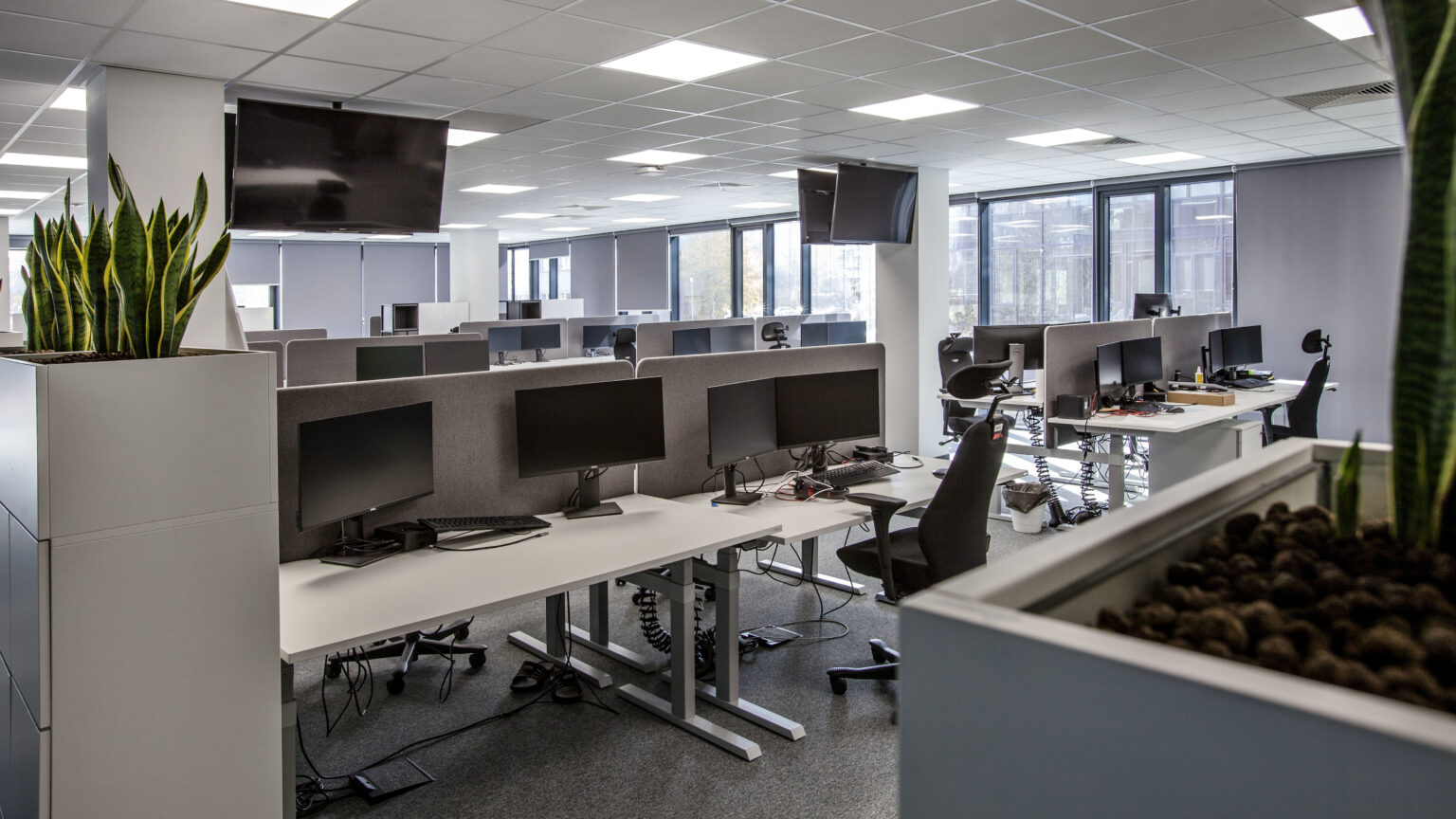 Strefa Open Space Assa Abloy z biurkami i monitorami Sony zawieszonymi pod sufitem