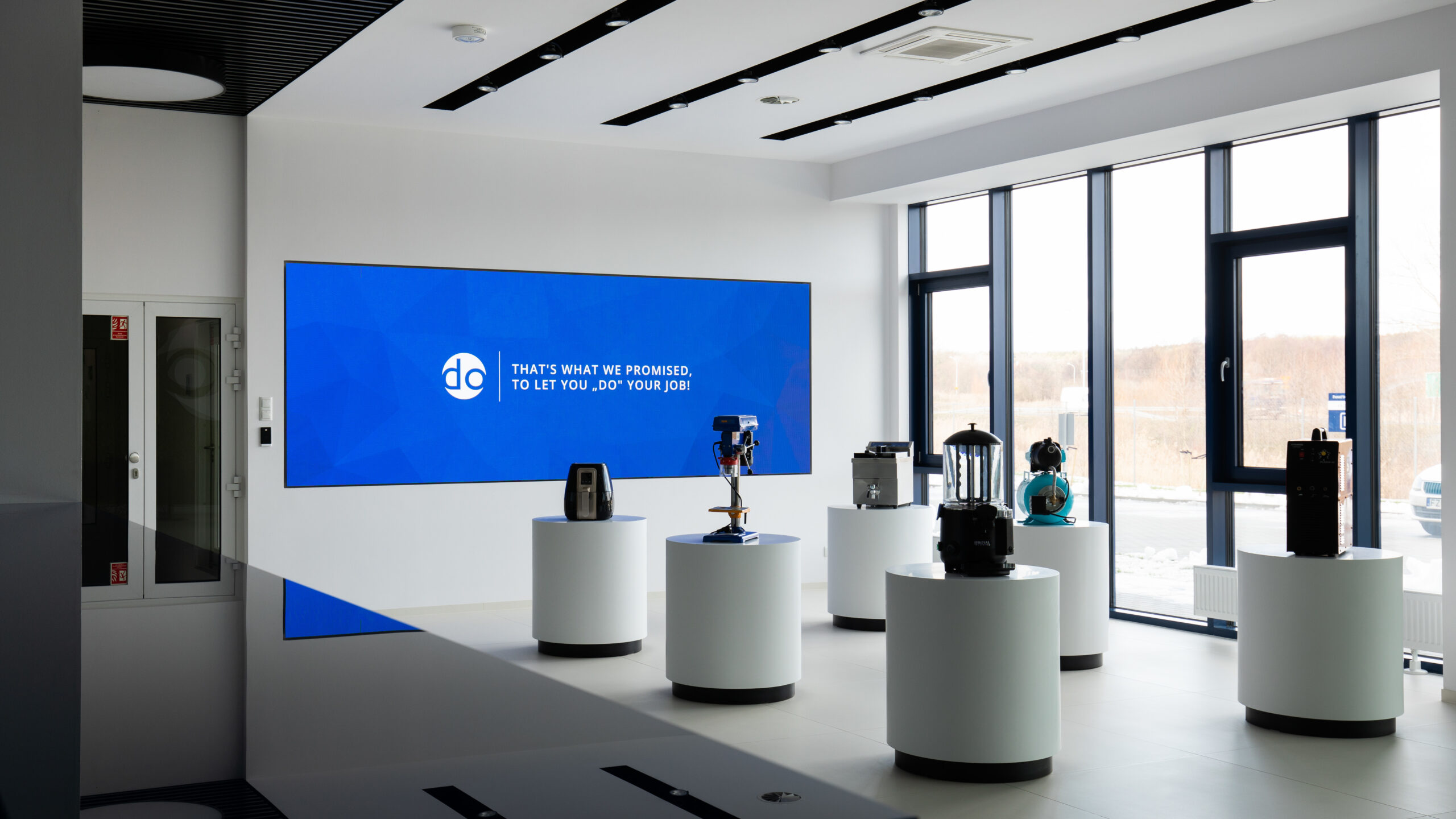 Lobby siedziby Expondo w Zielonej Górze z ekranem LED na ścianie i produktami na postumentach – realizacja PROAV