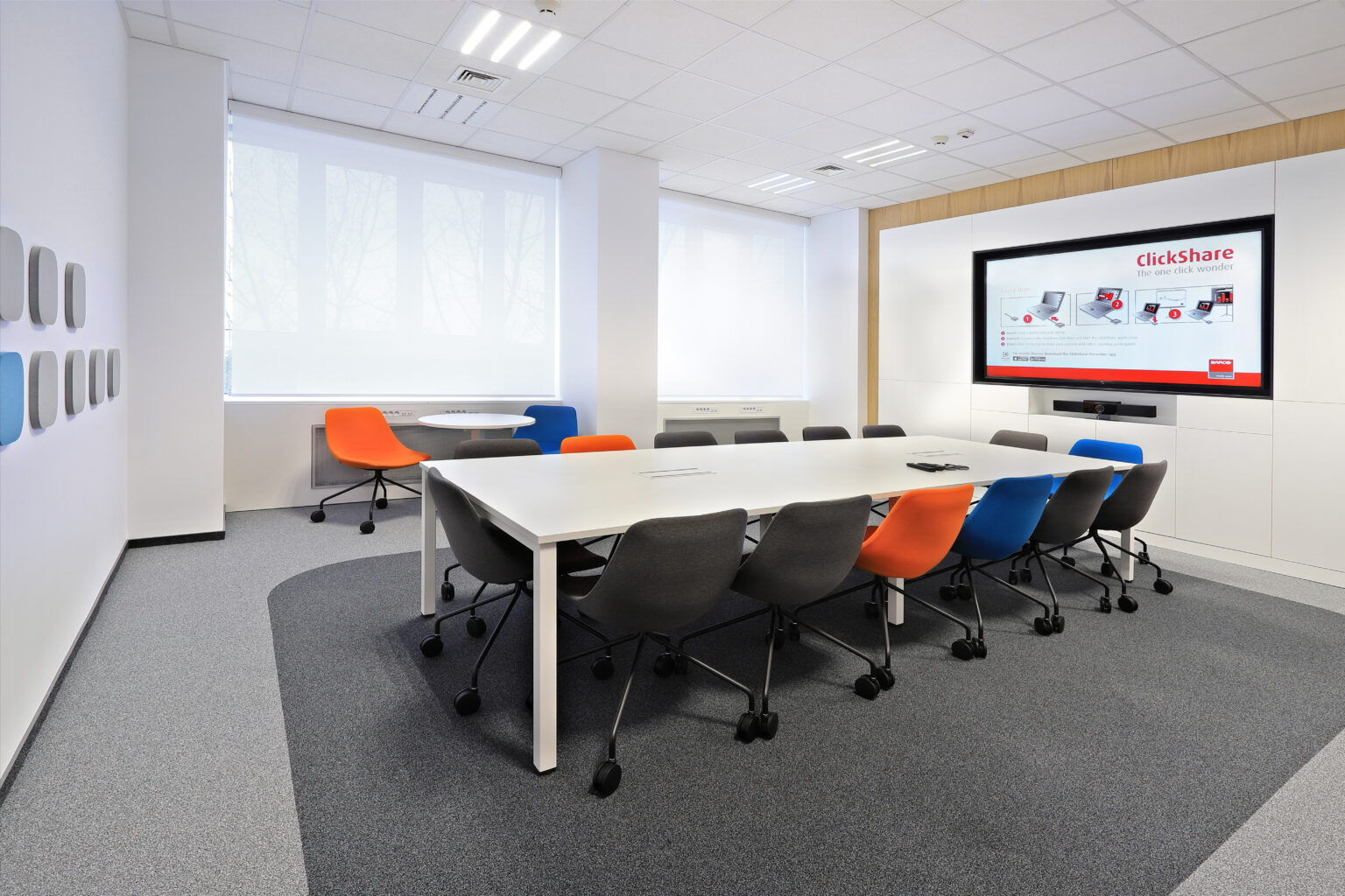 Mniejsza sala konferencyjna Siemens z monitorem LG, stołem i krzesłami na szarym dywanie