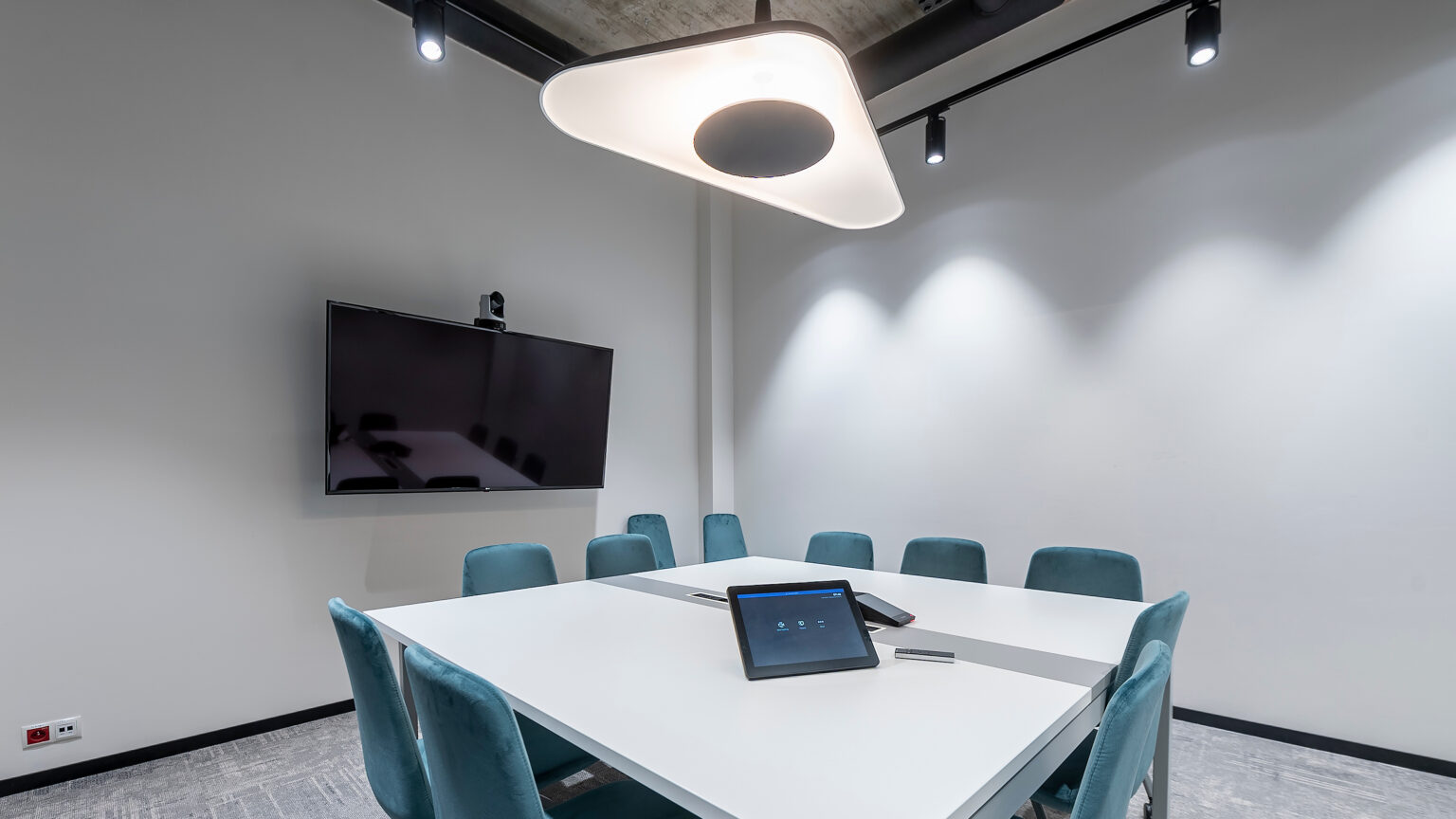 Sala konferencyjna IDEMIA z monitorem LG, kamerą Poly i panelem dotykowym na stole