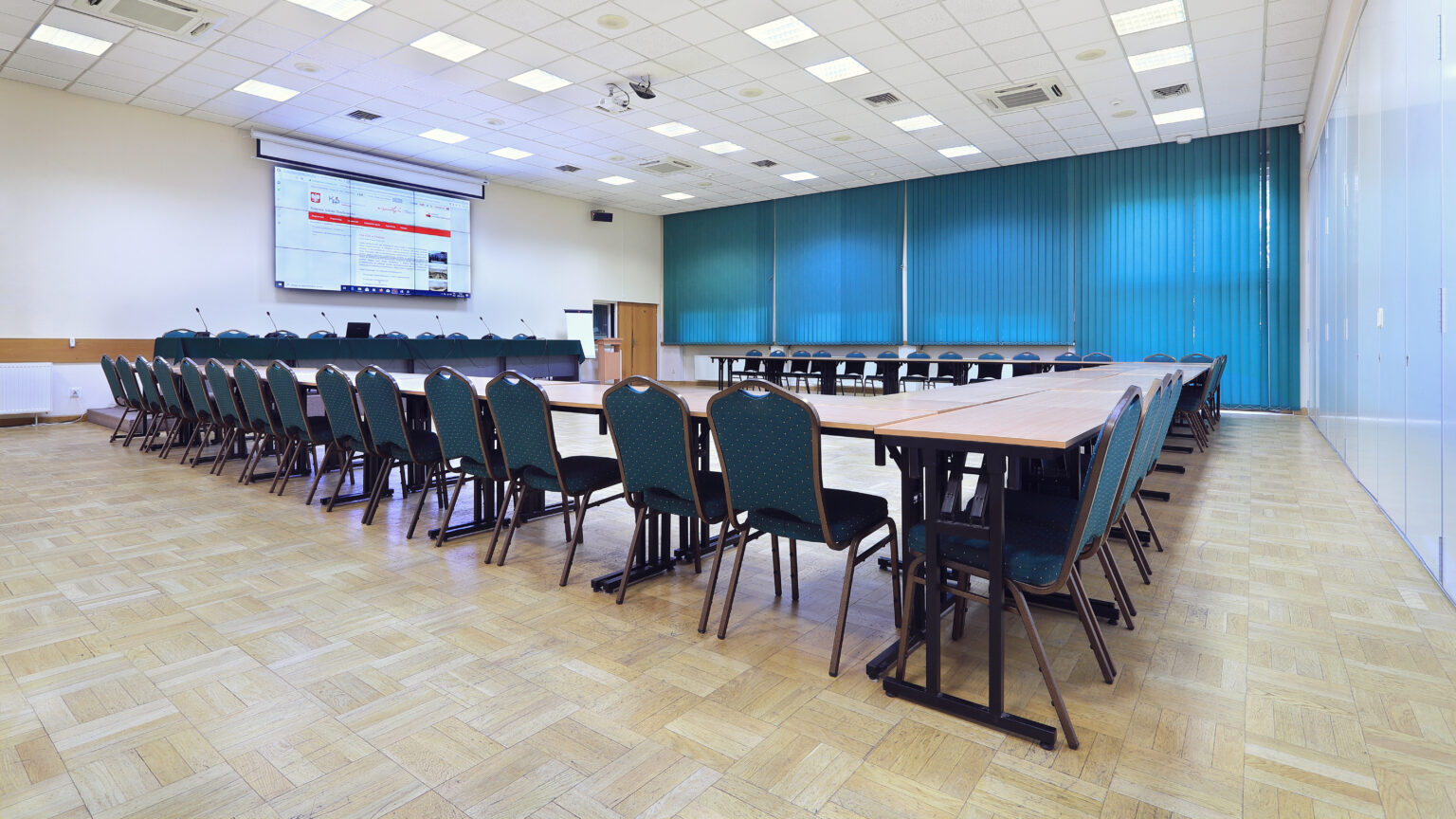 Sala wykładowa Krajowej Szkoły Skarbowości w Otwocku ze ścianą wizyjną i stołami