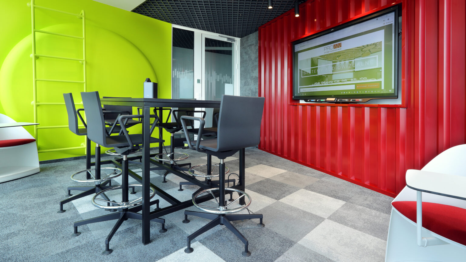 Sala w stylu kontenera kolejowego w biurze GATX Rail Poland z monitorem i wysokim stołem