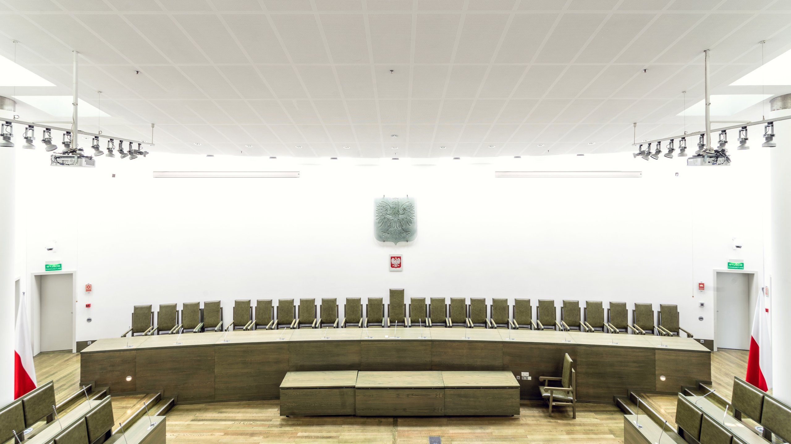 Bright Supreme Court courtroom with benches, the national emblem and ceiling-mounted projectors