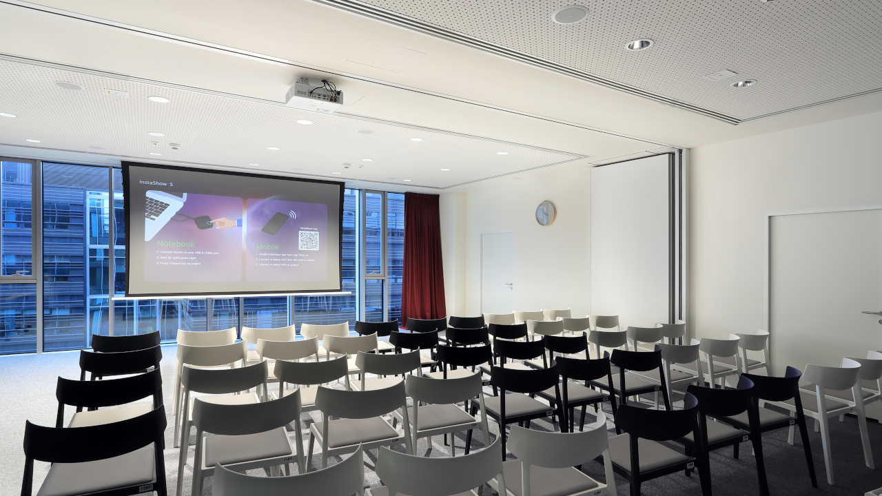 Sala konferencyjna PSI Pharma z ekranem projekcyjnym i krzesłami w układzie teatralnym